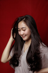 Obraz premium Asian woman taking photo on a red background. Happy Asian woman. Beautiful asian woman with long and straight hair.