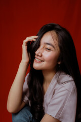 Fototapeta premium Asian woman taking photo on a red background. Happy Asian woman. Beautiful asian woman with long and straight hair.