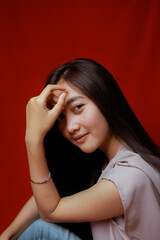 Fototapeta premium Asian woman taking photo on a red background. Happy Asian woman. Beautiful asian woman with long and straight hair.