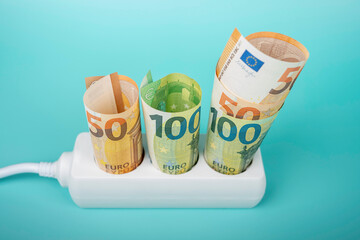 Euro money banknotes plugged in power strip extension cord on light blue background. Electricity prices increasing every month. Rising electric price and expensive energy concept