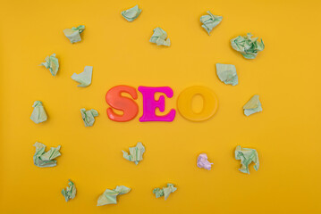 Crumpled balls of paper on yellow background. Top view seo text. Minimalistic seo concept