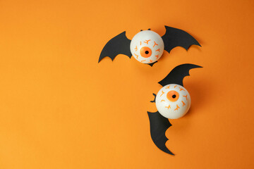 toy white eyes with bat wings on an orange background , a creative Halloween concept