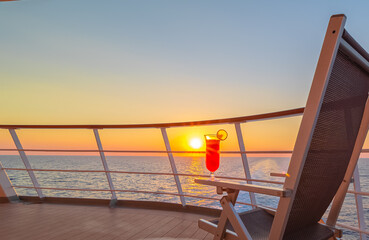Vue d'une chaise longue avec un cocktail sur le pont d'un navire de croisière au coucher de soleil...