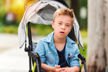 Portrait of a little boy with down syndrome sit on stroller