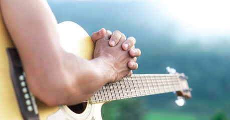 Man praying on acoustic guitar, Close up and focus at hand.