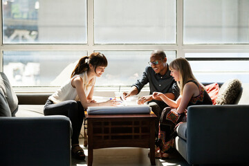 Business people checking blue prints on table in creative office