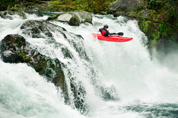 Whitewater kayaker descending waterfall in forest