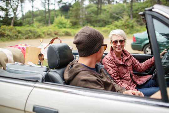 Happy woman sitting with man in convertible