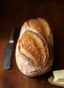 Close-up of bread loaf with knife and cheese on wooden table