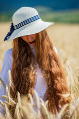 Woman with long wavy red hair and freckles on her face, wearing classic hat on natural background. - 529278029