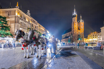 Naklejka na ściany i meble Krakow city in the evening in Poland, Main Square in the Old Town, illuminated St. Mary Church and Cloth Hall (Sukiennice).
