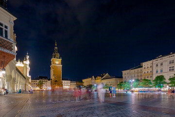 Fototapeta premium Krakow city in the evening in Poland, Main Square in the Old Town, illuminated St. Mary Church and Cloth Hall (Sukiennice).