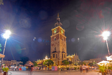 Fototapeta premium Krakow city in the evening in Poland, Main Square in the Old Town, illuminated St. Mary Church and Cloth Hall (Sukiennice).