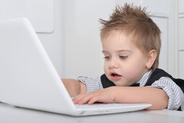 Little handsome boy sits with a computer 