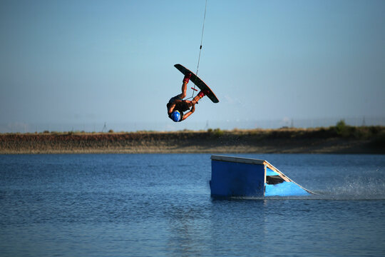 Kiteboarder performing stunt on kicker in lake
