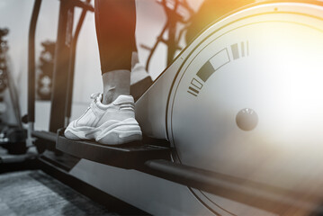 Woman training on elliptical trainer in gym