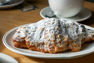 almond croissant on a plate, with shadow, selective focus, close-up
