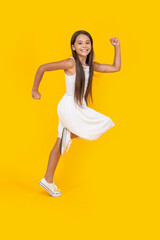 Fototapeta na wymiar happy teen girl in white dress running on yellow background