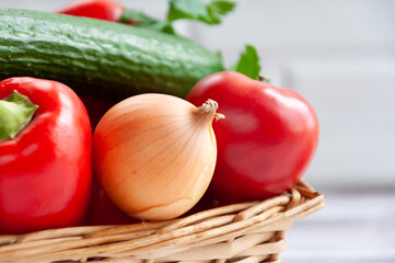 Various vegetables in a wicker basket. Close-up. Food. Tomatoes, onions, peppers, cucumbers.