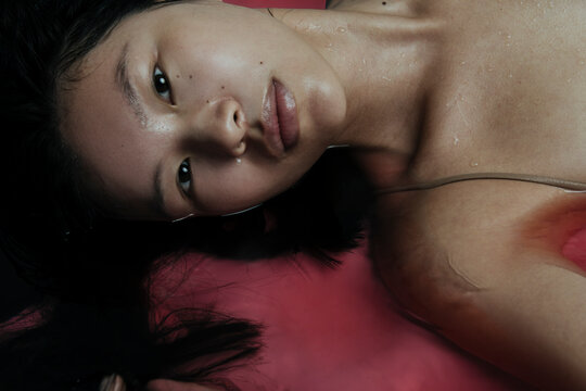 Beautiful asian girl in a bathtub with a pink salt bomb having a relaxing treatment.