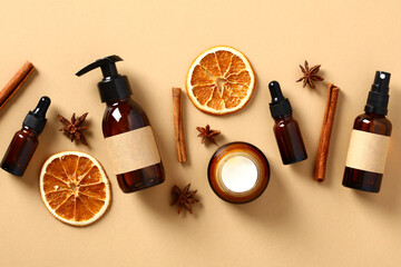Set of fall natural skincare cosmetics with dried orange slices, cinnamon sticks, anise stars. Amber glass bottes packaging design.