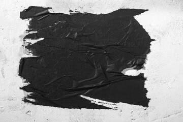 Scraps of black paper on a white wall. - obrazy, fototapety, plakaty