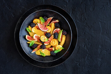 Autumn fig salad. Whole vegan paleo fruit and vegetable fall salad idea. Homemade salad bowl with figs, orange, black berries and kumquat