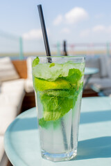 Mojito cocktail in a glass with mint, lime and ice on a blue table. Refreshing drink. selective focus