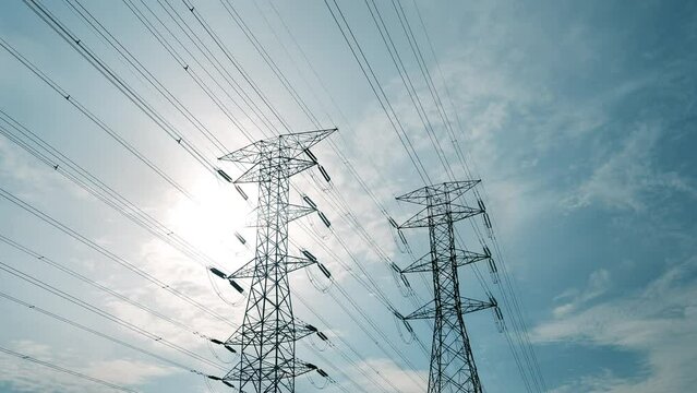 A close up timelapse footage with noise effect electic transmission tower with moving cloud and sun insight. Electric and energy concept.