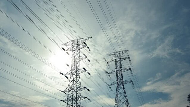 A zoom in timelapse footage with noise effect electic transmission tower with moving cloud and sun insight. Electric and energy concept.