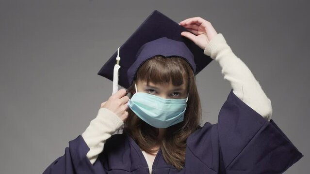 Graduation girl wearing cap and taking off  protective face mask. Female student smiling and throwing hat in the air.
