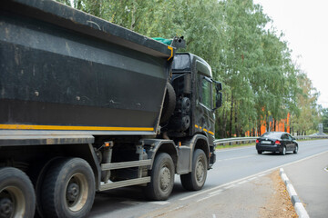 Black truck on road. Freight transport on highway. Car with body. Great trailer.