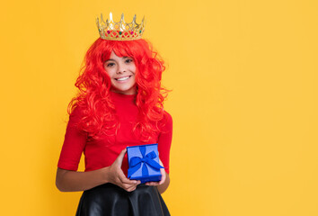 glad child in crown with present box on yellow background
