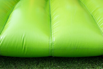 Green inflatable trampoline. Obstacle course. Details of amusement park.