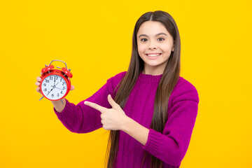 Portrait of teenage girl with clock alrm, time and deadline. Studio shot isolated on yellow background.