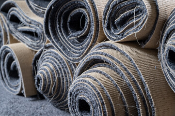 Stacked old carpet rolls in a grey room.
