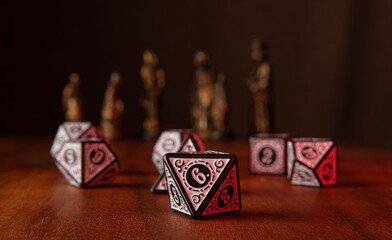 RPG dice, beautiful RPG dice on rustic wood, dark background with figures, selective focus.