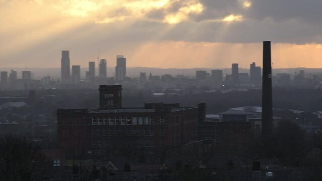 Panoramic view of Manchester city skyline at sunset, view from a vantage point at Oldham. The tall chimney is of an old mill.