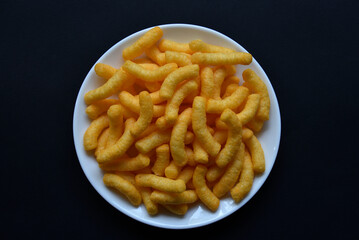 Corn salted and peppered chips on a white plate. Delicious breakfast of corn chips on a black background.