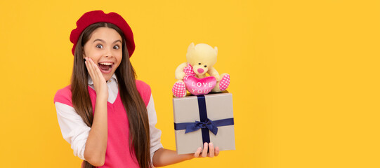 surprised teen girl in french beret hold toy present and gift box on yellow background. Kid girl with gift, horizontal poster. Banner header with copy space.