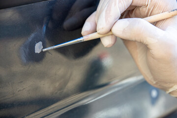 Spot tinting of chips with a brush. auto painter restores the paint layer of the car.
