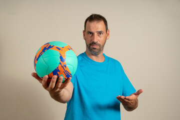 A handsome latin man playing soccer holding a soccer ball over beige background offering a handshake as a greeting and welcome. Successful business