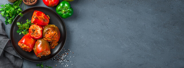 Stuffed peppers with fresh herbs in a black plate on a graphite background. Top view, copy space