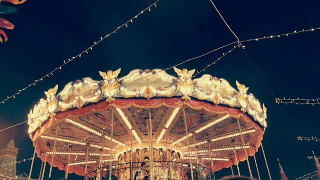 Festive garlands and a beautiful, colorful carousel against the background of the night sky on Red Square create a fun, New Year's mood. Shot in motion