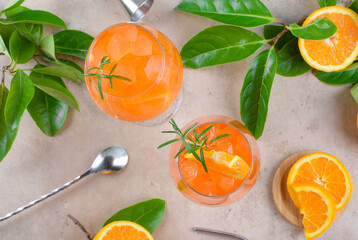 Classic italian aperitif aperol spritz cocktail in two wineglasses with ice cubes and slice of orange on beige stone background, traditional summer fresh iced drink, top view, flat lay