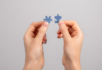 Hands connecting matching jigsaw puzzle pieces. Two details representing companies merging, joint venture, partnership, solution finding. - obrazy, fototapety, plakaty