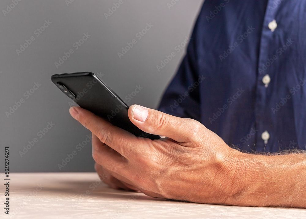 Poster man hands with phone. male sitting at table and using smartphone for work, personal interests.