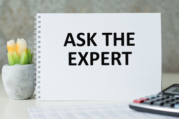 Text ASK THE EXPERT on notepad with office tools, pen on financial report