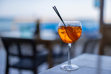 orange Aperol spritz cocktail sitting with straws and ice on a table 