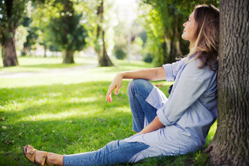 Obraz premium young woman relaxing in green summer parkwith beautiful light